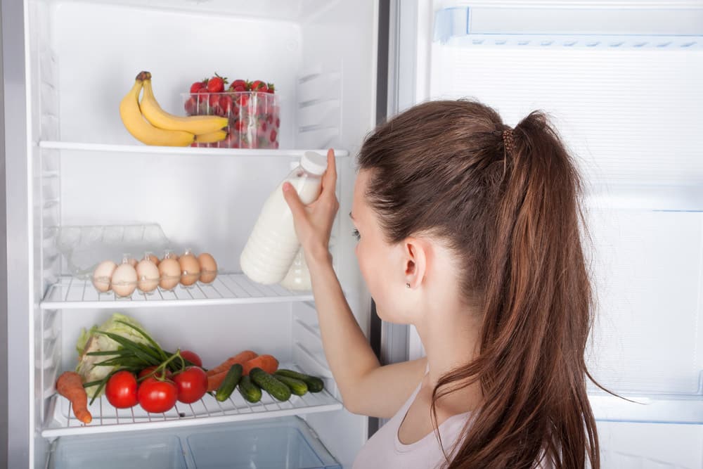 女人在打开的冰箱里选择了牛奶